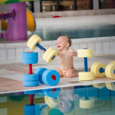 Baby hält Aquafitness-Hantel in die Höhe
