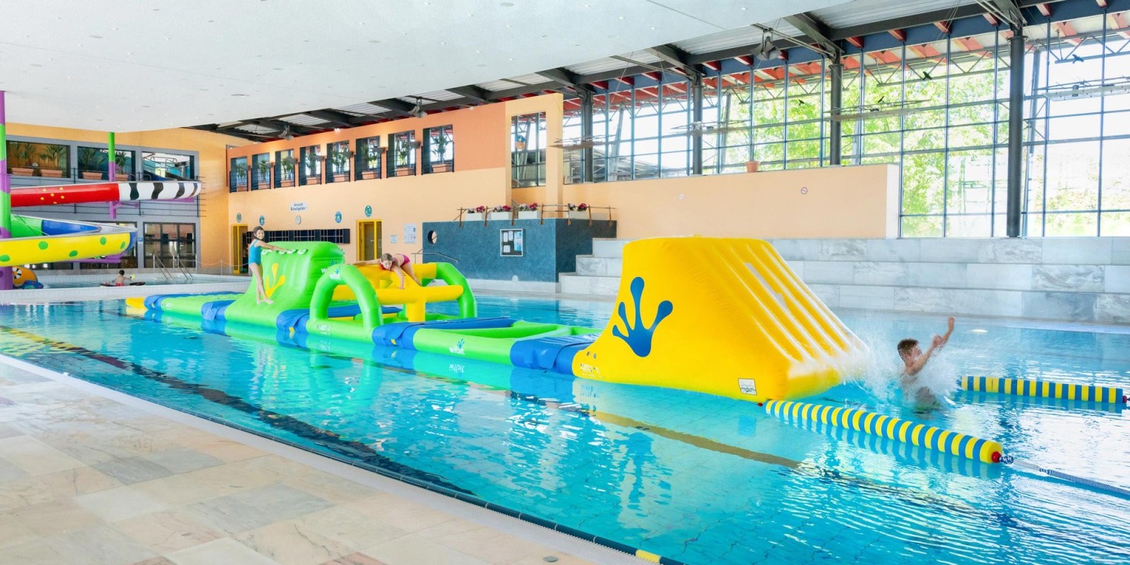 Kinder klettern über den Aqua Parcours im Hallenbad neufun